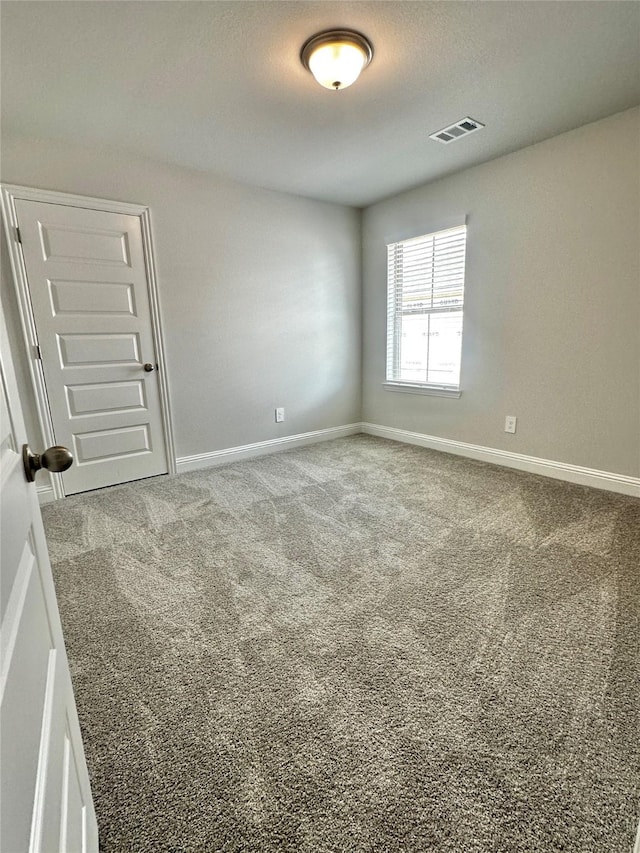 empty room featuring carpet flooring, visible vents, and baseboards