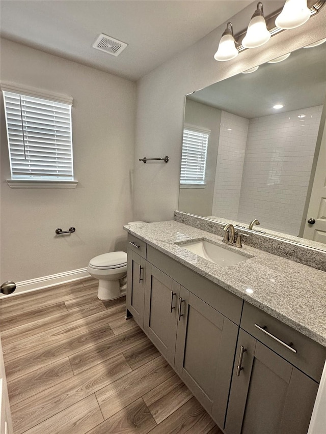 bathroom with baseboards, visible vents, toilet, wood finished floors, and vanity