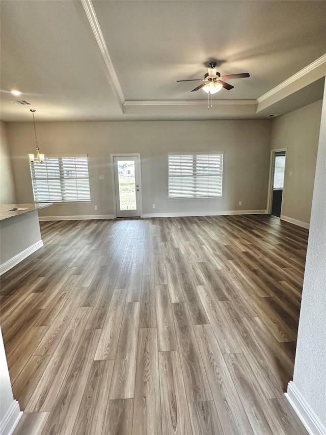 unfurnished living room featuring ornamental molding, a raised ceiling, baseboards, and dark wood-style floors