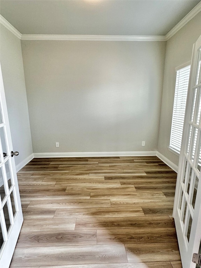 empty room with french doors, crown molding, and wood finished floors