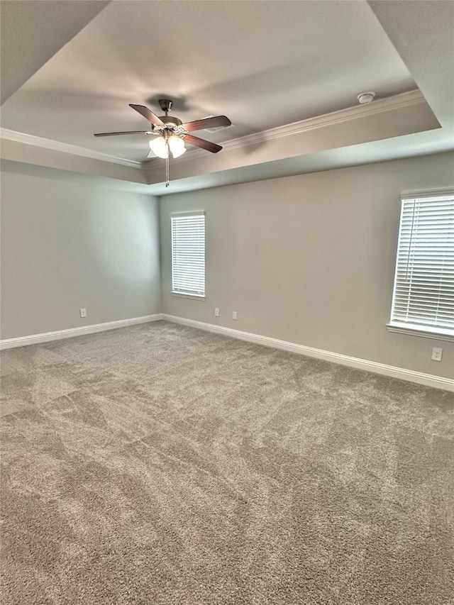 carpeted empty room featuring baseboards, a raised ceiling, a ceiling fan, and ornamental molding