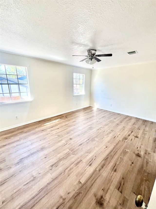 empty room with a textured ceiling, light hardwood / wood-style flooring, and ceiling fan