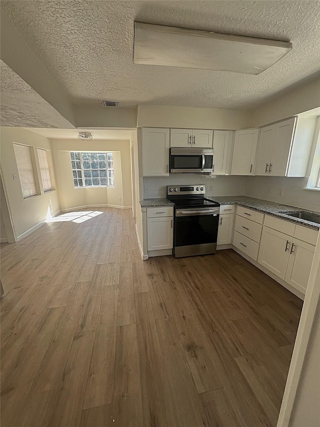 kitchen with white cabinetry, light hardwood / wood-style flooring, and stainless steel appliances