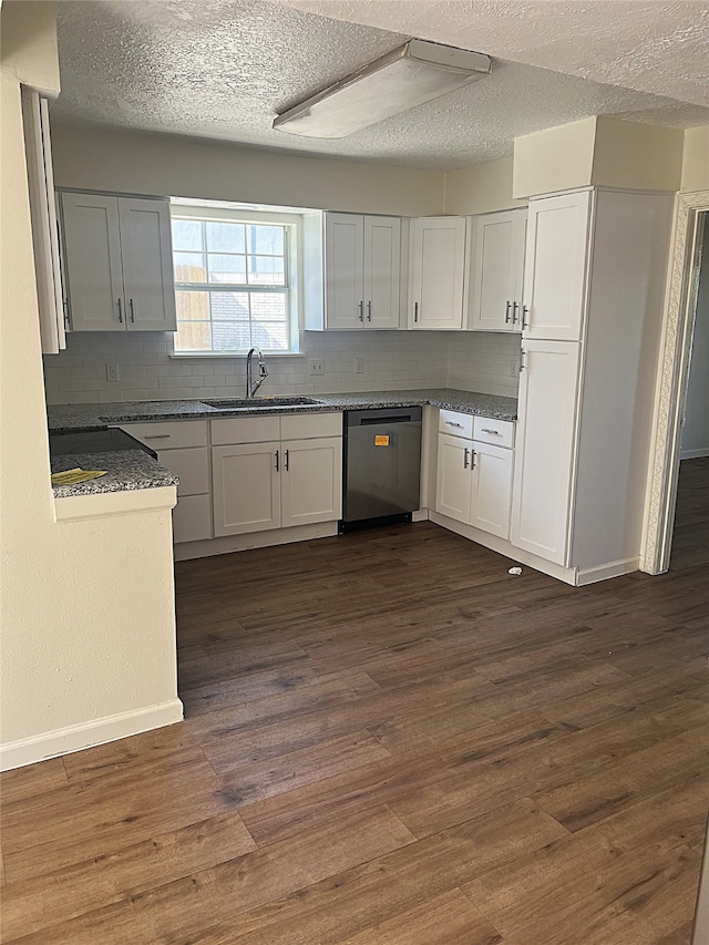 kitchen featuring dark hardwood / wood-style floors, white cabinetry, sink, backsplash, and stainless steel dishwasher