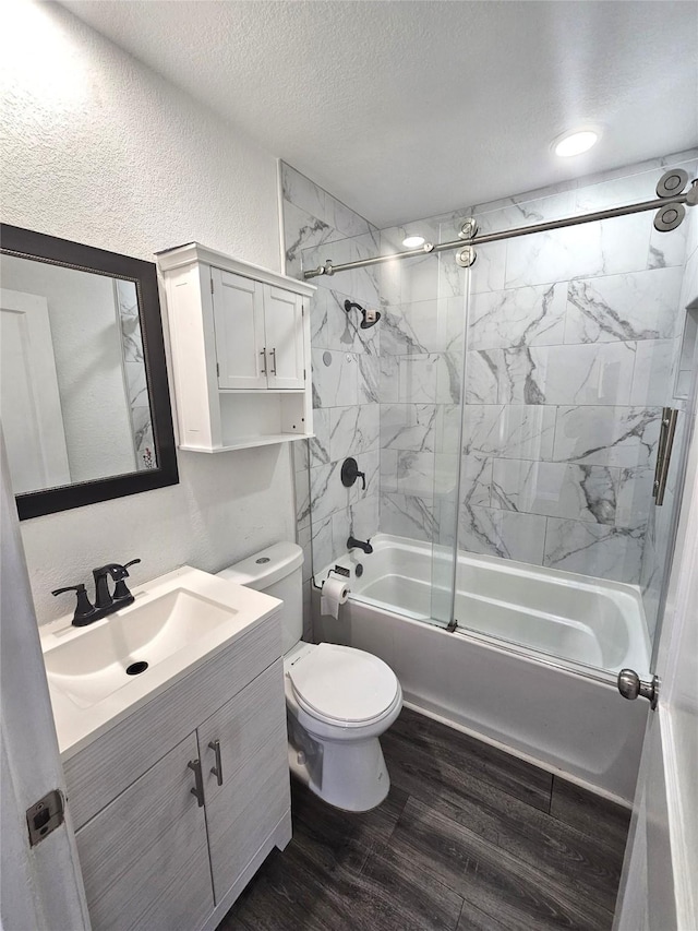 full bathroom featuring tiled shower / bath, hardwood / wood-style flooring, vanity, toilet, and a textured ceiling