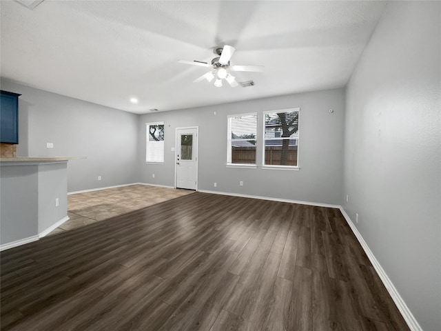 unfurnished living room featuring ceiling fan and dark hardwood / wood-style flooring