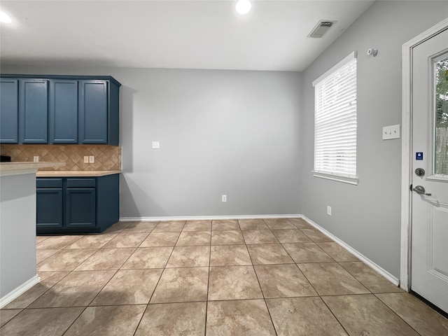 kitchen with blue cabinets, light tile patterned flooring, plenty of natural light, and tasteful backsplash