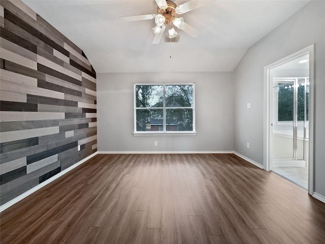 spare room with vaulted ceiling, wooden walls, dark hardwood / wood-style flooring, and a healthy amount of sunlight