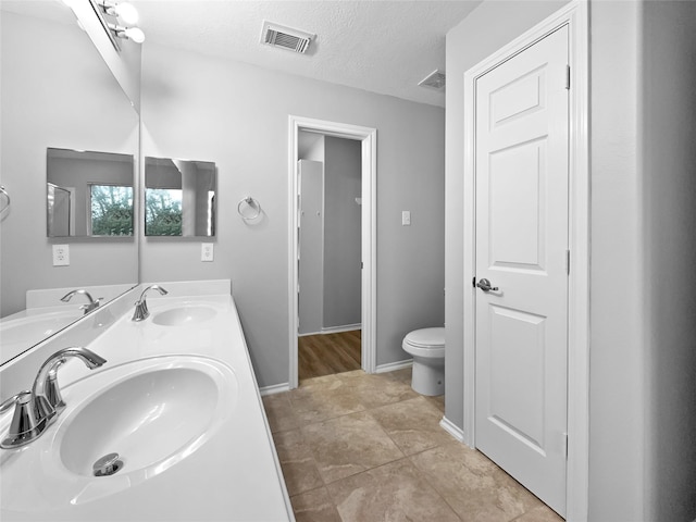 bathroom with tile patterned flooring, vanity, a textured ceiling, and toilet