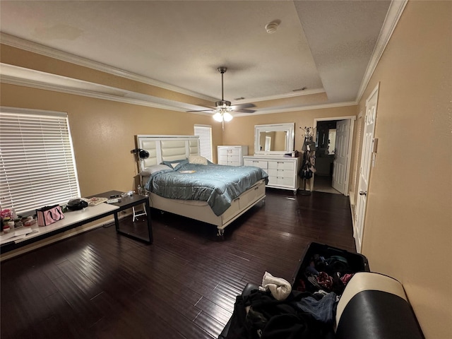 bedroom with dark wood-type flooring, ceiling fan, ornamental molding, and a tray ceiling