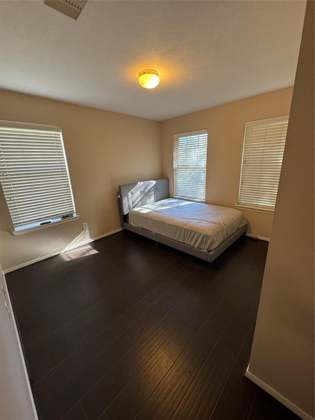 bedroom with dark hardwood / wood-style floors and a textured ceiling