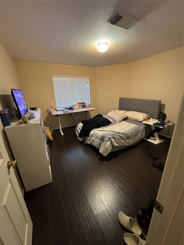 bedroom featuring a textured ceiling and dark hardwood / wood-style flooring