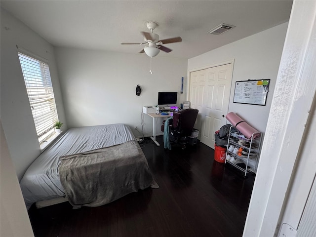 bedroom with dark wood-type flooring, ceiling fan, and a closet