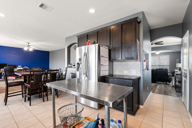 kitchen with dark brown cabinetry, light tile patterned floors, backsplash, and ceiling fan