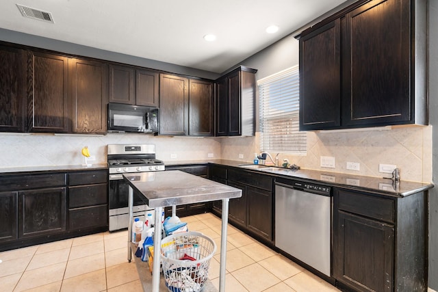 kitchen featuring dark brown cabinetry, sink, light tile patterned flooring, and appliances with stainless steel finishes