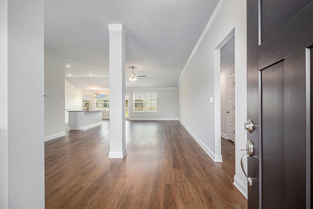 interior space with ornate columns, sink, ornamental molding, ceiling fan, and dark wood-type flooring