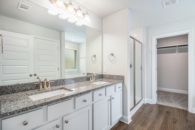 bathroom with an enclosed shower, vanity, and wood-type flooring