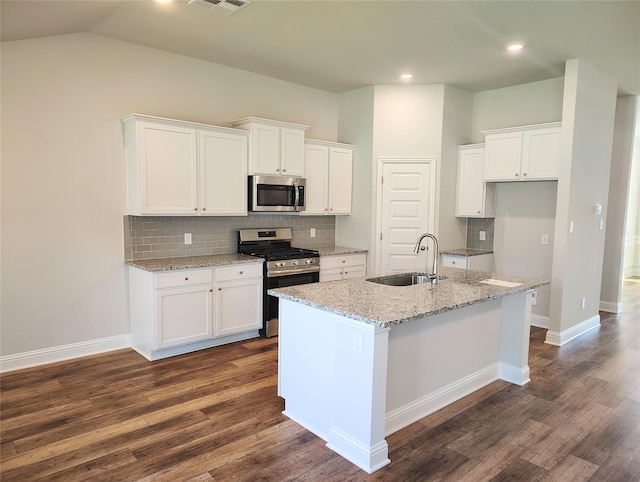 kitchen featuring sink, appliances with stainless steel finishes, white cabinetry, light stone counters, and a center island with sink