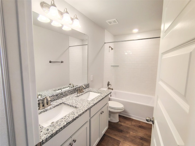 full bathroom featuring vanity, tiled shower / bath, hardwood / wood-style flooring, and toilet