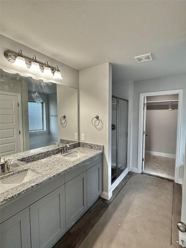 bathroom featuring double vanity, a stall shower, a sink, and visible vents