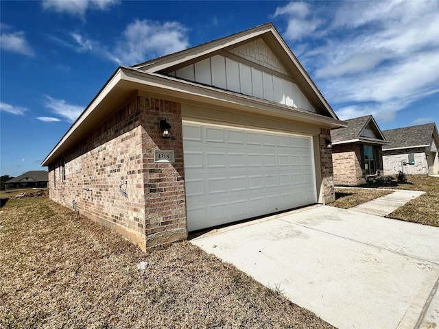 view of side of property with driveway, brick siding, board and batten siding, and an attached garage