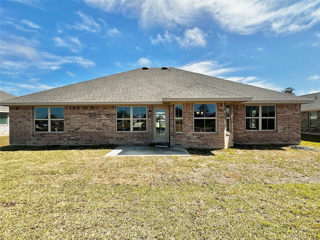 rear view of house featuring a patio area, roof with shingles, a lawn, and brick siding