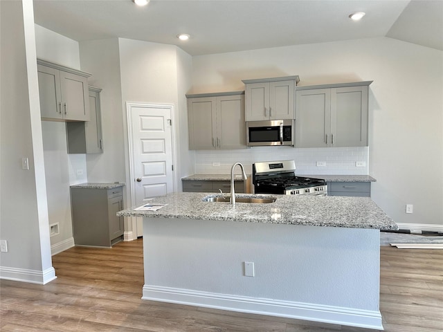 4318 Karam Lndg, Dickinson, TX 77539 - kitchen featuring a center island with sink, light wood-style flooring, a sink, gray cabinetry, and stainless steel appliances