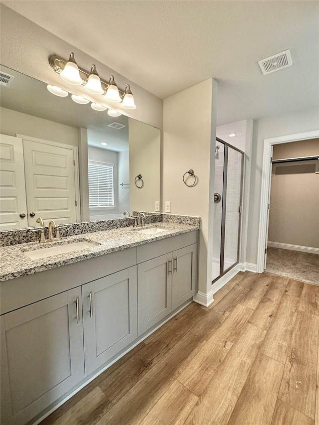 4318 Karam Lndg, Dickinson, TX 77539 - bathroom with visible vents, a sink, wood finished floors, a shower stall, and double vanity