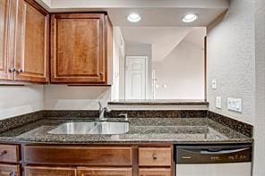 kitchen with dishwasher, sink, and dark stone countertops