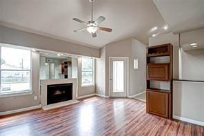 unfurnished living room featuring hardwood / wood-style flooring, ceiling fan, plenty of natural light, and vaulted ceiling