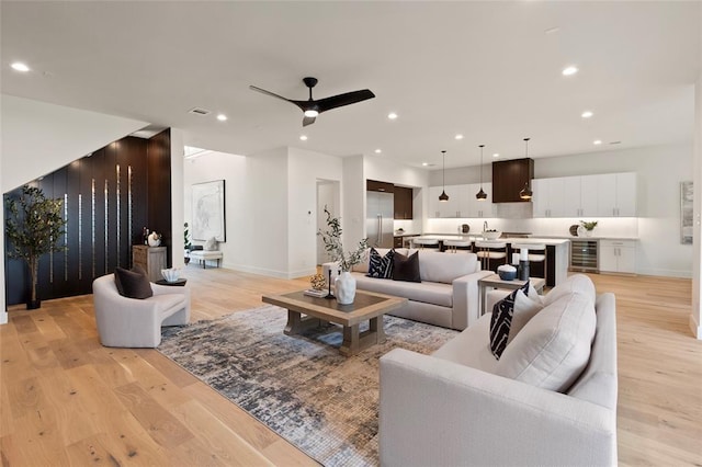 living room with ceiling fan, beverage cooler, and light hardwood / wood-style flooring