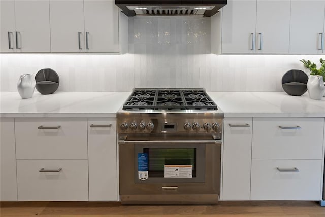 kitchen featuring decorative backsplash, stainless steel stove, exhaust hood, and white cabinets