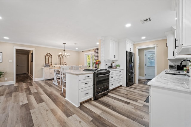 kitchen with gas range, white cabinetry, light stone counters, refrigerator, and hanging light fixtures