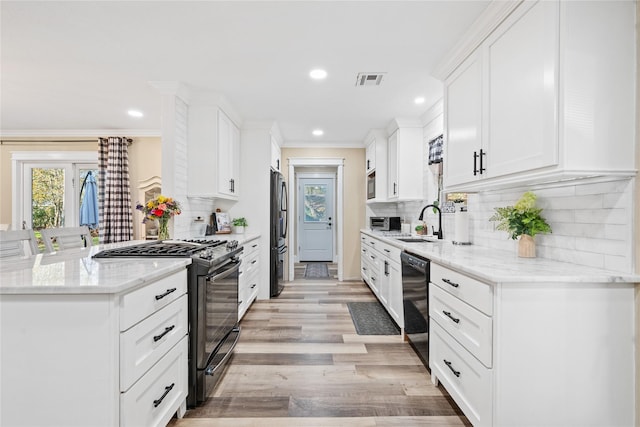 kitchen featuring white cabinetry, sink, stainless steel appliances, crown molding, and light stone countertops