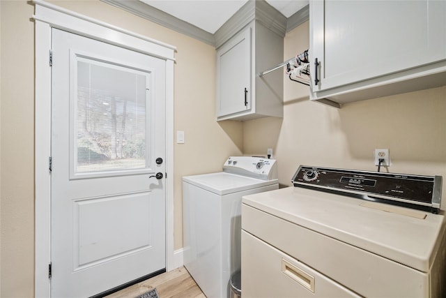 washroom featuring cabinets, light hardwood / wood-style floors, and washer and dryer