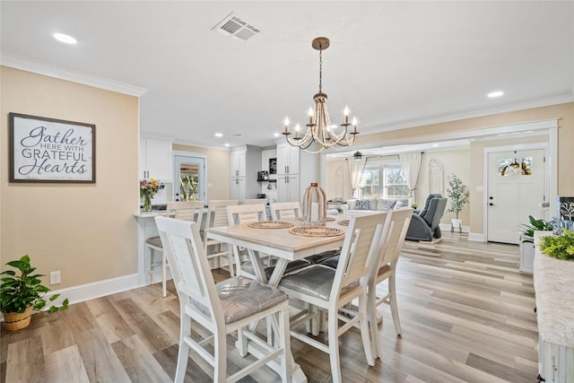 dining space featuring an inviting chandelier, ornamental molding, and light hardwood / wood-style floors