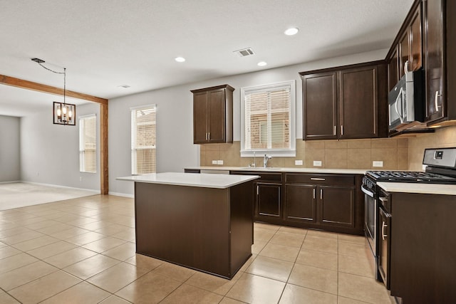 kitchen featuring light tile patterned flooring, appliances with stainless steel finishes, a kitchen island, and hanging light fixtures