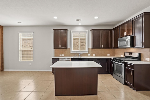 kitchen with sink, appliances with stainless steel finishes, dark brown cabinets, a center island, and tasteful backsplash