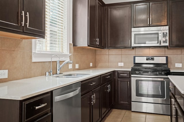 kitchen featuring sink, light tile patterned floors, dark brown cabinets, stainless steel appliances, and decorative backsplash