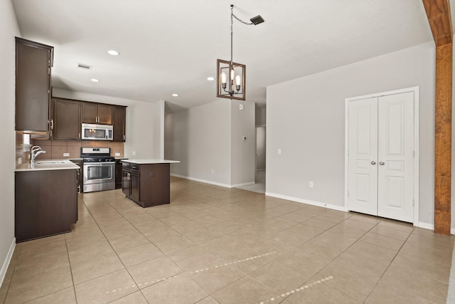 kitchen with appliances with stainless steel finishes, decorative light fixtures, decorative backsplash, a center island, and dark brown cabinets