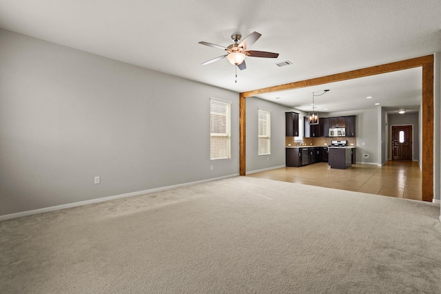 unfurnished living room featuring ceiling fan and light carpet