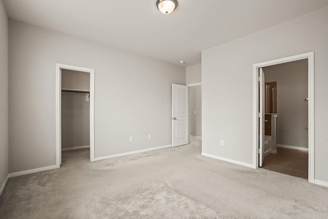 unfurnished bedroom featuring connected bathroom, a spacious closet, light colored carpet, and a closet