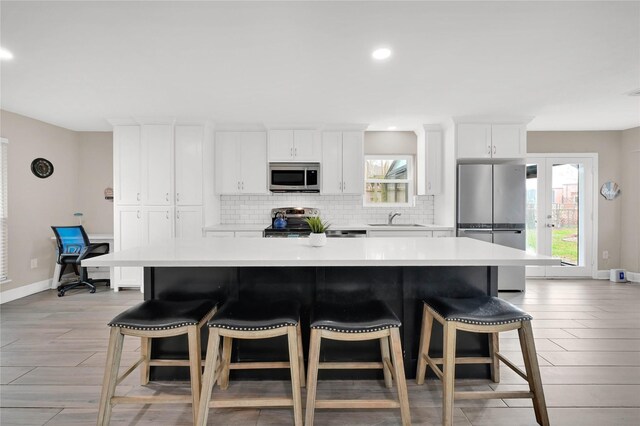 kitchen with white cabinetry, sink, stainless steel appliances, and a spacious island