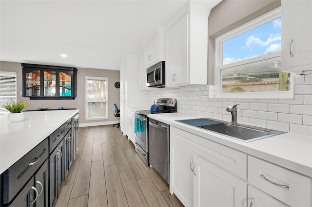 kitchen with stainless steel appliances, white cabinets, light countertops, and a sink