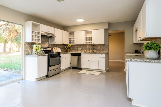 kitchen with light stone countertops, white cabinetry, appliances with stainless steel finishes, and backsplash