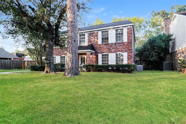 colonial house featuring a front yard and central air condition unit