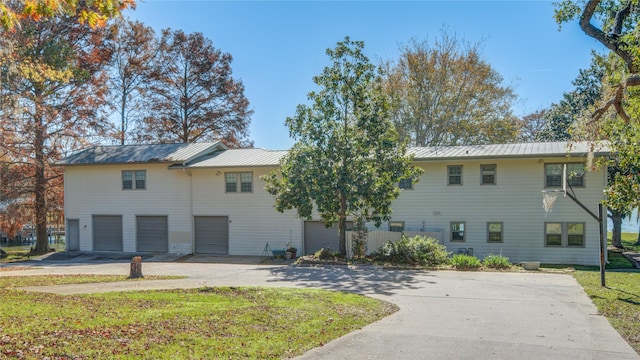 view of property with a garage, metal roof, and concrete driveway