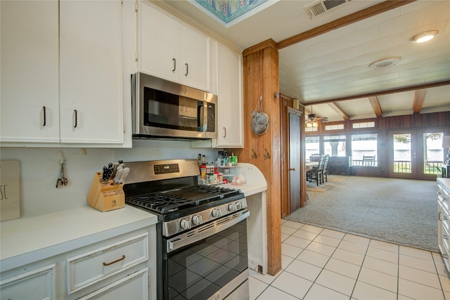 kitchen with beam ceiling, stainless steel appliances, light countertops, light colored carpet, and open floor plan