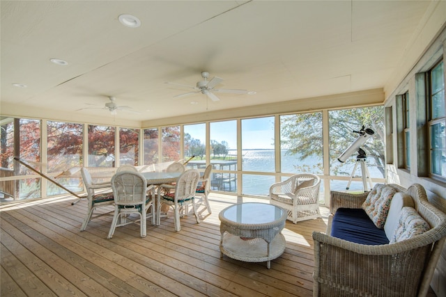 sunroom with ceiling fan and a water view