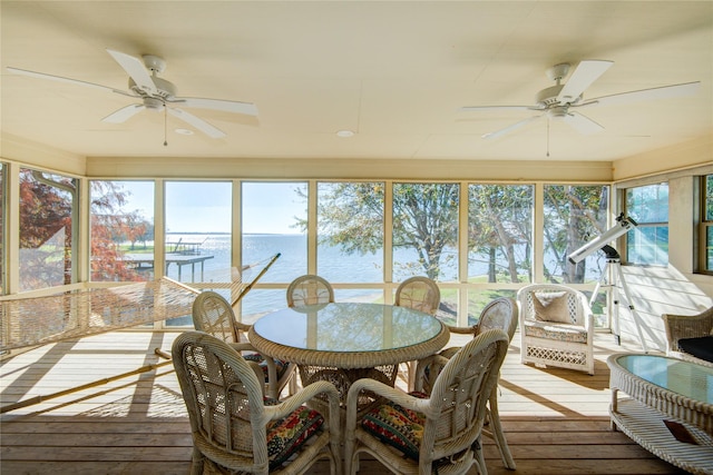 sunroom with a water view, a healthy amount of sunlight, and a ceiling fan